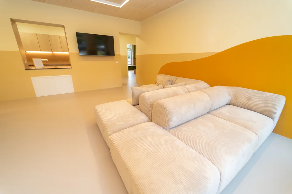 Sofalandschaft vor einer warmgelben Wand im gemeinsamen Wohnbereich